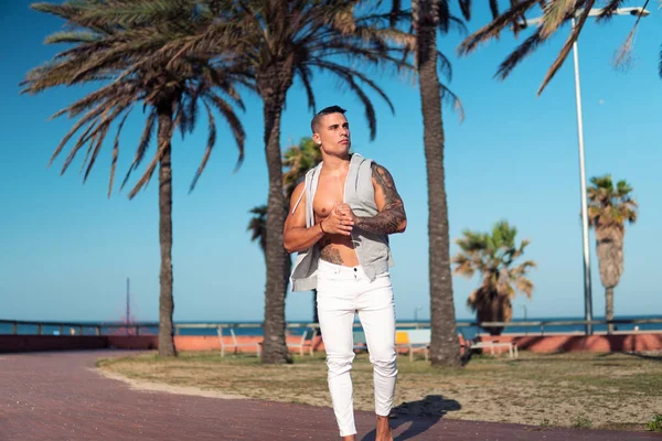 Tattooed bodybuilder sexy male coach at the beach.