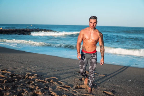 Tatuado culturista sexy entrenador masculino en la playa . —  Fotos de Stock