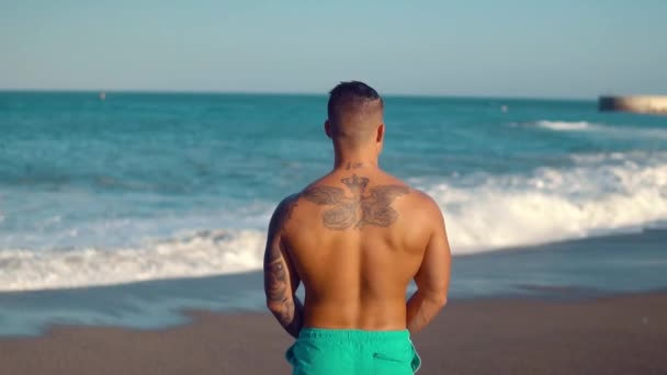 Getatoeëerde bodybuilder sexy mannelijke coach op het strand. — Stockvideo