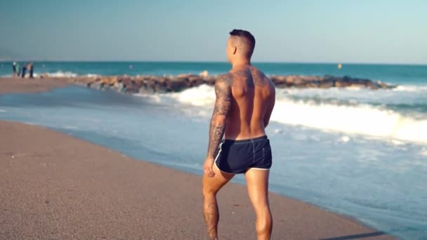 Татуйований культурист сексуальний тренер чоловіків на пляжі . — стокове відео