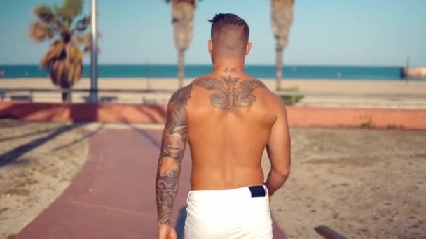 Tatuerade bodybuilder sexig manlig tränare på stranden. — Stockvideo