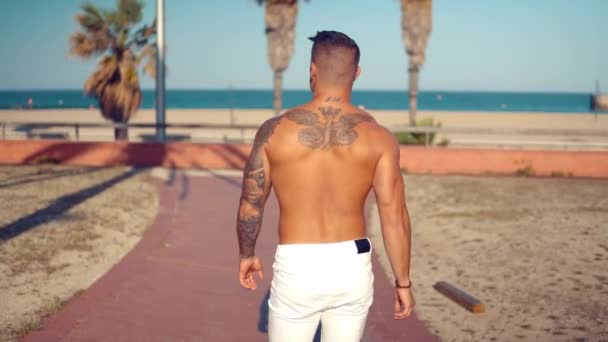 Tatuado culturista sexy entrenador masculino en la playa . — Vídeo de stock