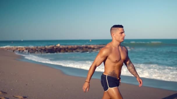 Tatuerade bodybuilder sexig manlig tränare på stranden. — Stockvideo