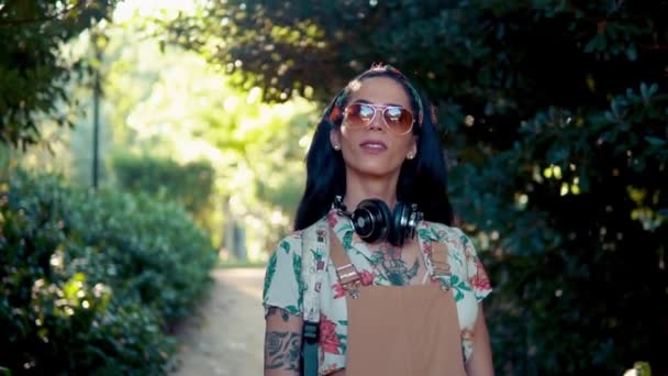 Modèle transgenre portant des lunettes de soleil dans le parc vert — Video