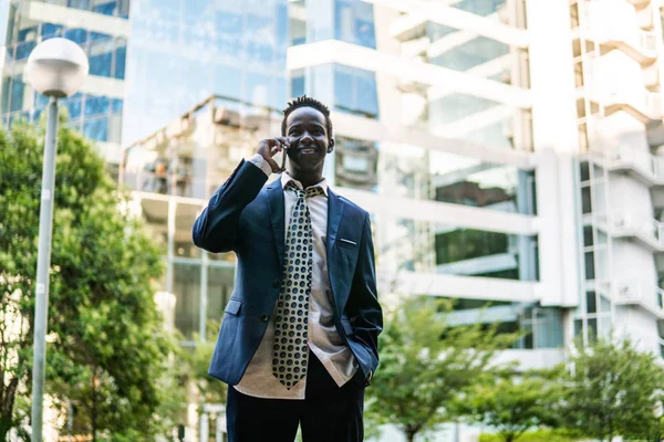 Hombre de negocios afroamericano sosteniendo teléfono móvil con traje azul —  Fotos de Stock