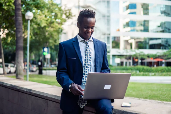 Empresário afro-americano segurando notebook laptop vestindo terno azul — Fotografia de Stock