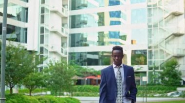 Mavi takım elbise giyen Afro-Amerikan işadamı yürüyor