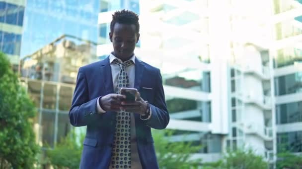 Hombre de negocios afroamericano sosteniendo teléfono móvil con traje azul — Vídeos de Stock