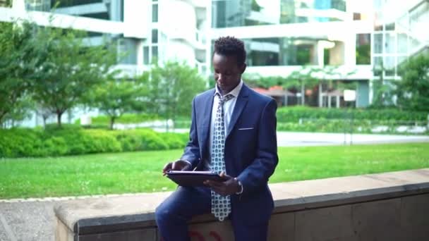 파란색 정장을 입고 노트북 노트북을 들고 있는 아프리카계 미국인 사업가 — 비디오