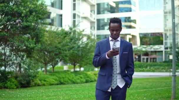 Hombre de negocios afroamericano sosteniendo teléfono móvil con traje azul — Vídeo de stock