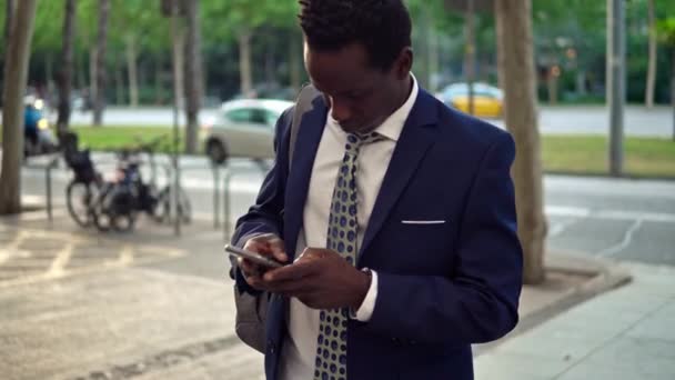Hombre de negocios afroamericano sosteniendo teléfono móvil con traje azul — Vídeo de stock