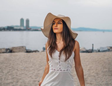 Beyaz elbise ve pamela şapka ayakta giyen güzel kadın