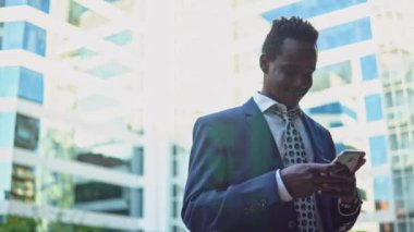 Mavi takım elbise giyen cep telefonu tutan Afro-Amerikalı işadamı