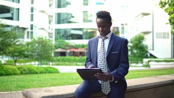 Empresário afro-americano segurando notebook laptop vestindo terno azul — Vídeo de Stock