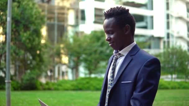 Un homme d'affaires afro-américain tenant un ordinateur portable portant un costume bleu — Video