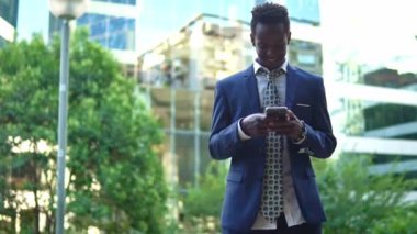 Mavi takım elbise giyen cep telefonu tutan Afro-Amerikalı işadamı