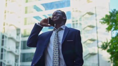 Mavi takım elbise giyen cep telefonu tutan Afro-Amerikalı işadamı