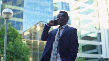 Mavi takım elbise giyen cep telefonu tutan Afro-Amerikalı işadamı