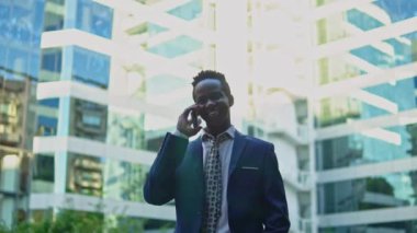 Mavi takım elbise giyen cep telefonu tutan Afro-Amerikalı işadamı