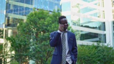 Mavi takım elbise giyen cep telefonu tutan Afro-Amerikalı işadamı