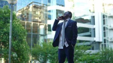 Mavi takım elbise giyen cep telefonu tutan Afro-Amerikalı işadamı