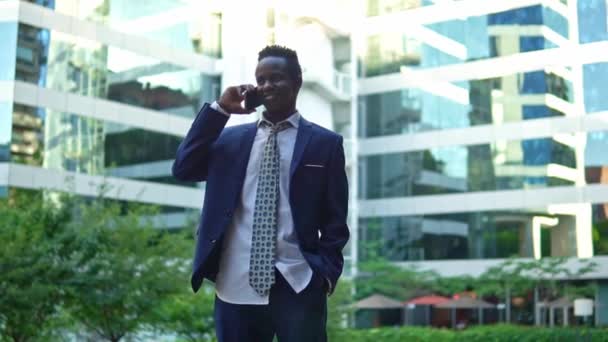 Hombre de negocios afroamericano sosteniendo teléfono móvil con traje azul — Vídeos de Stock