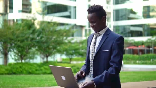 Empresário afro-americano segurando notebook laptop vestindo terno azul — Vídeo de Stock