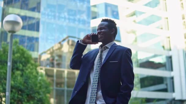 Афроамериканский бизнесмен держит мобильный телефон в синем костюме — стоковое видео