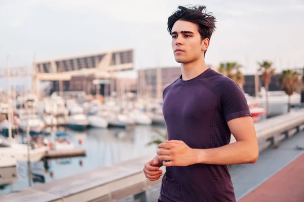 Young athletic man running at park during skyscrapers background