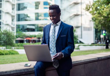 Mavi takım elbise giyen dizüstü bilgisayar tutan Afro-Amerikalı işadamı