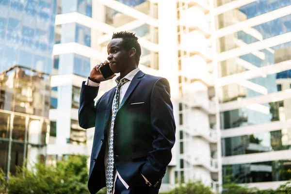 Empresário afro-americano segurando celular vestindo terno azul — Fotografia de Stock