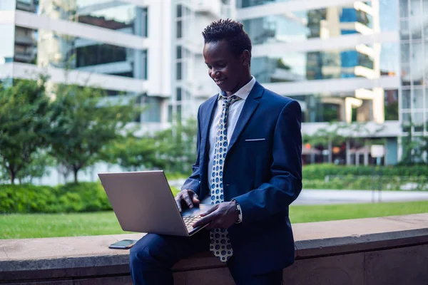 Empresário afro-americano segurando notebook laptop vestindo terno azul — Fotografia de Stock