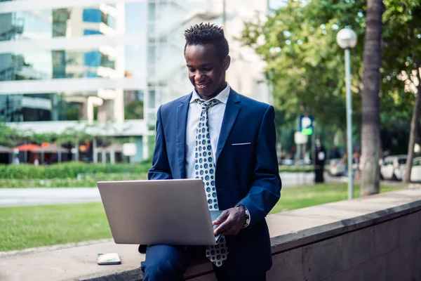 Hombre de negocios afroamericano sosteniendo portátil portátil con traje azul —  Fotos de Stock