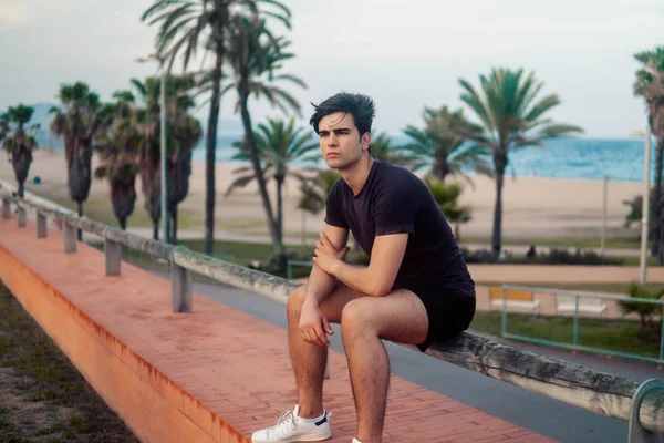 Hombre atlético joven después de correr en el parque con antecedentes rascacielos —  Fotos de Stock