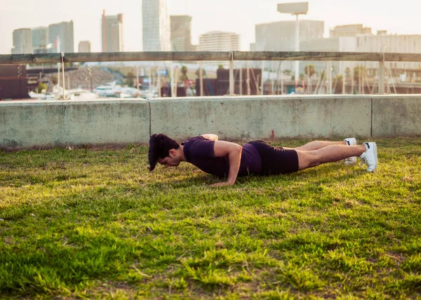 Hombre atlético joven haciendo ejercicios de flexiones en el parque —  Fotos de Stock