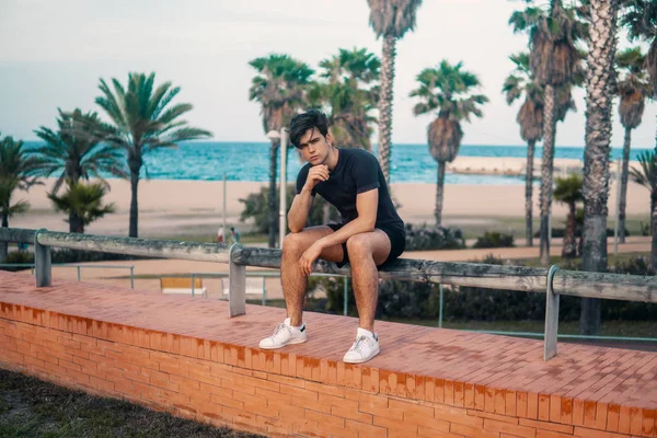 Hombre atlético joven después de correr en el parque con antecedentes rascacielos —  Fotos de Stock