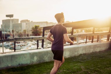 Gökdelenler arka plan ile parkta çalışan genç atletik adam