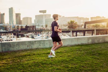 Gökdelenler arka plan ile parkta çalışan genç atletik adam