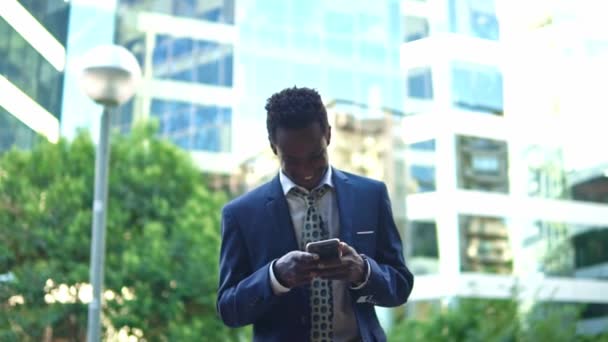 Hombre de negocios afroamericano sosteniendo teléfono móvil con traje azul — Vídeos de Stock