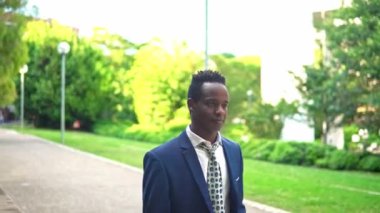 Mavi takım elbise giyen Afro-Amerikan işadamı yürüyor