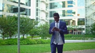 Mavi takım elbise giyen cep telefonu tutan Afro-Amerikalı işadamı