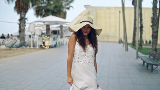 Mujer bonita con vestido blanco y sombrero de pamela caminando — Vídeos de Stock