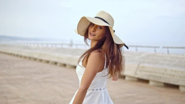 Mujer bonita con vestido blanco y sombrero de pamela caminando — Vídeo de stock