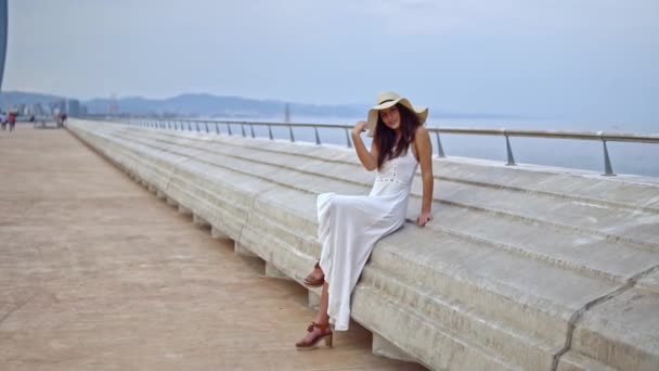 Pretty woman wearing white dress and pamela hat sitting — Stock Video