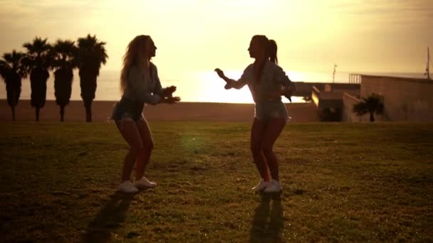 Szczęśliwy siostry lub przyjaciele skoki na plaży ciesząc zachód słońca — Wideo stockowe