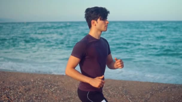 Ung atletisk man som springer på stranden. Hälsokoncept — Stockvideo