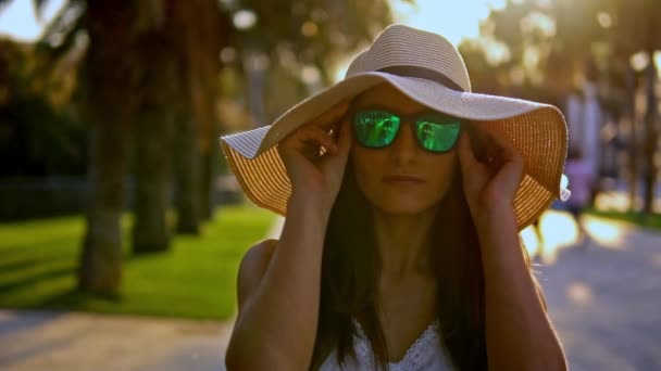 Mujer bonita con vestido blanco y sombrero de pamela caminando — Vídeo de stock