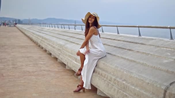 Mooie vrouw het dragen van witte jurk en Pamela hoed zitten — Stockvideo