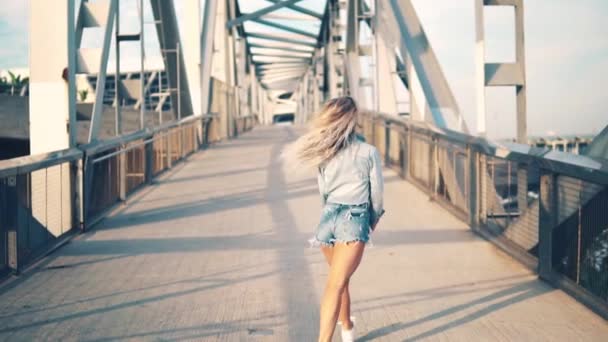 Hermosa chica feliz felizmente corre a través del puente . — Vídeos de Stock