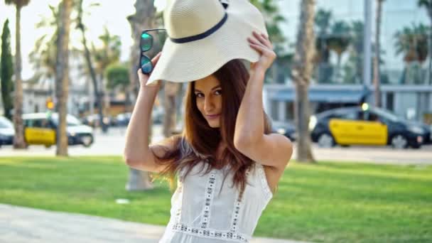 Mujer bonita con vestido blanco y sombrero de pamela caminando — Vídeo de stock